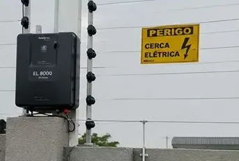Central de choque e placa de advertência em cerca elétrica industrial