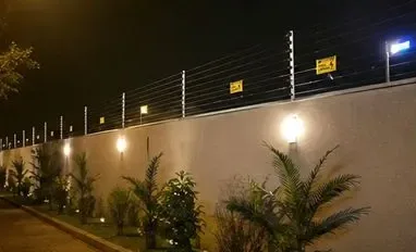 Cerca elétrica em muro com iluminação, à noite