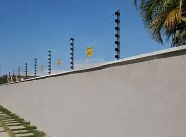 Fileira de hastes com isoladores no topo de um muro residencial