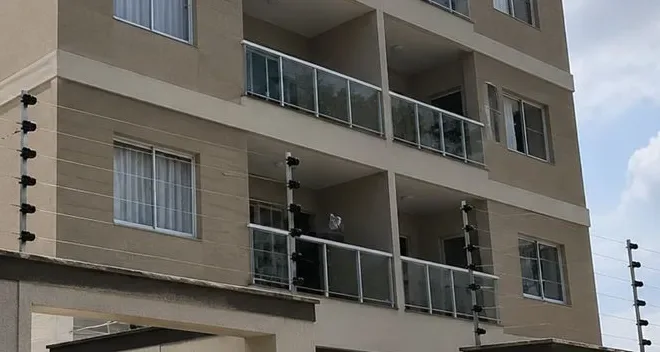 Hastes com isoladores e fios da cerca elétrica no alto do muro de um prédio